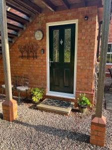 eine schwarze Tür auf einem Backsteinhaus mit Pflanzen in der Unterkunft Hanley Swan, The Garden Flat in Madresfield + 2 Fotos