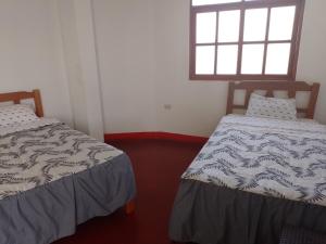 two beds in a room with a window at Casa Duna Sur in Huacachina