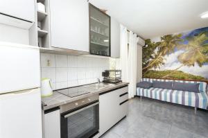 eine Küche mit weißen Schränken und einem Sofa in einem Zimmer in der Unterkunft Apartment Milena in Srima
