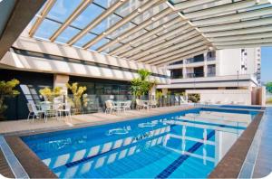 a pool with tables and chairs and a building at Flat Aeroporto Congonhas in Sao Paulo
