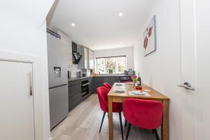 a kitchen with a wooden table and red chairs at CONTRACTORS FAVOURITE, LUXURY LIVING, LARGE PREMIUM HOUSE, NEWLY BUILT, FREE PARKING FOR UP TO 4 VEHICLES, GREAT ACCESS TO CENTRAL LUTON & THE M1 and A6 in Luton