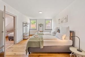 two beds in a bedroom with white walls and wood floors at Sali Homes - Schwäbisch Hall - Altstadt GG 95 in Schwäbisch Hall