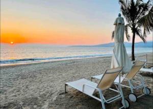 twee stoelen en een parasol op een strand bij Nuevo Vallarta Beachfront Condo! in Bucerías