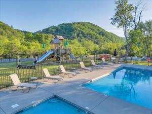 une piscine avec des chaises et une aire de jeux avec un toboggan dans l'établissement Cozy Cabin Near Dollywood with Parking, à Pigeon Forge