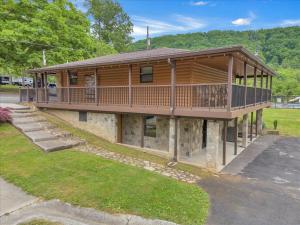 une grande maison en bois avec une terrasse dans une cour dans l'établissement Cozy Cabin Near Dollywood with Parking, à Pigeon Forge