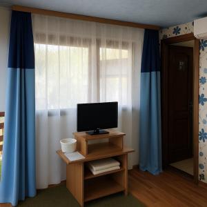 a living room with a television and blue curtains at Cabana Ogradena in Eşelniţa