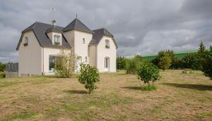 a white house with a black roof on a field at Au clair de lune in Saint-Rémy-sous-Barbuise