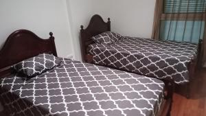 Un dormitorio con dos camas con edredón blanco y negro. en Costa Lodges, Shared Room Funchal or Santa Cruz, en Santa Cruz