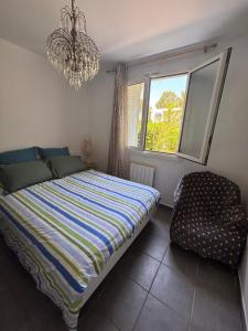 Un dormitorio con una cama, una silla y una lámpara de araña. en Appartement au bord de mer, en La Ciotat