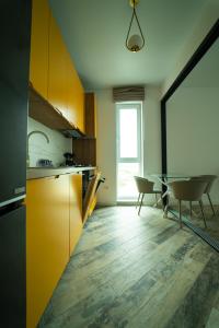a kitchen with yellow cabinets and a table with chairs at CristAlex Sunset in Constanţa
