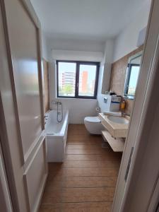 une salle de bain avec deux lavabos et une baignoire et des toilettes dans l'établissement Miriam Apart, à Mamaia Nord – Năvodari