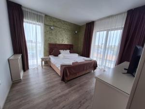une chambre avec un lit, une télévision et des fenêtres dans l'établissement Miriam Apart, à Mamaia Nord – Năvodari