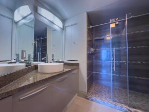 Un baño con dos lavabos y una ducha de cristal. en MVR Need Space Style - Book This Suite, en Miami