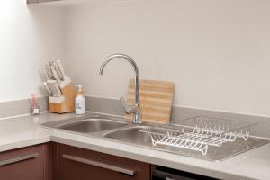 a kitchen sink with a dish drying rack on it at Closer to Home Luxury Apartments in Midrand +23 photos