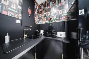 a black kitchen with a sink and a microwave at Harry Potter - Séjour magique à Poudlard in Saint-Étienne +29 photos