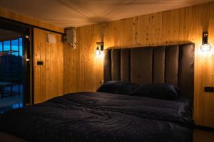 a bedroom with a bed with a wooden wall at Fanar Chalet in Glodu +45 photos