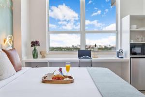 Una bandeja de fruta y una bebida en una cama con ventana. en MVR Suite Floor to Ceiling Wow in Every Room, en Miami
