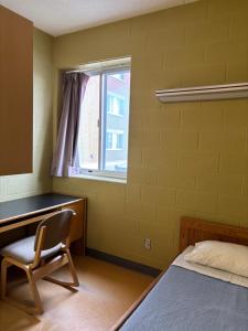a bedroom with a desk and a chair and a window at Hotel Laurier - King Street Residence in Waterloo