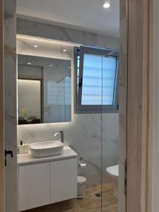 a white bathroom with a sink and a mirror at Toska Residence in Loutraki +36 photos