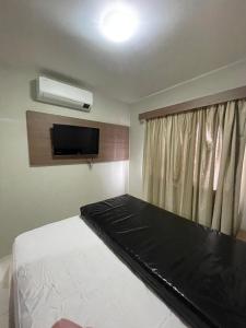 Un dormitorio con una cama y un televisor de pantalla plana. en Veredas do Rio Quente, en Rio Quente