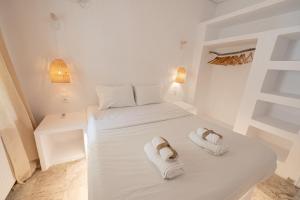 a white room with two beds and two towels at The White Rose Hotel in Poros