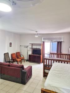 une chambre avec un lit, un canapé et une télévision dans l'établissement Ótima Kitnet pé na areia na praia de Pitangueiras c/ vista para o mar., à Guarujá