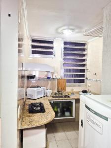 une cuisine avec un comptoir avec un micro-ondes dans l'établissement Ótima Kitnet pé na areia na praia de Pitangueiras c/ vista para o mar., à Guarujá