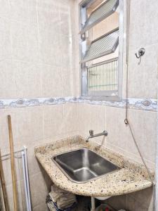 un lavabo dans une salle de bain carrelée avec une fenêtre dans l'établissement Ótima Kitnet pé na areia na praia de Pitangueiras c/ vista para o mar., à Guarujá