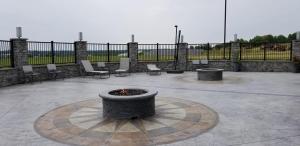 a fire pit in a patio with chairs and a fence at Garland Hotel in New Concord