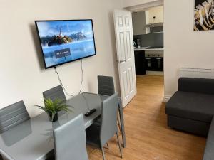 a dining room table with chairs and a television on a wall at Cozy Apartment, Parking, Wi-Fi, Sleeps 5 in Liverpool