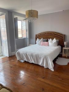 a bedroom with a bed with white sheets and pink pillows at Casa Amore in Montemor-o-Velho