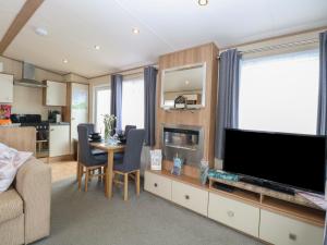 a living room with a television and a table with chairs at Seashell Lodge, 50 Foxburrow Hang in Great Yarmouth