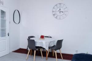 a dining room with a table and chairs and a clock at Spacious and Comfy Pad - Perfect for Long Stays & Contractors - Close to Sports Village, Leigh Market, and Mesnes Park - Easy Parking - Speedy Wi-Fi - Free On-Site or Nearby Parking - Private Luxury Garden in Leigh