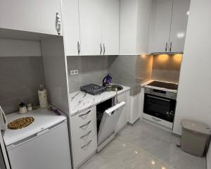 a small kitchen with white cabinets and a sink at New building Stupine G Top Location in Tuzla