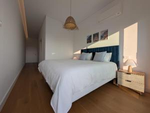a bedroom with a large white bed and a lamp at Breathtaking Oceanfront Living, Sunset Facing 3-Bedroom Flat in Acqua Residences in Funchal