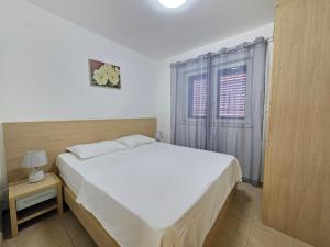 a bedroom with a white bed and a window at Blue Dream Apartment in Rafailovici