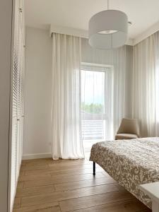 a bedroom with a bed and a chair and a window at Villa Mare in Gdańsk