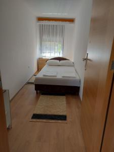 a small bedroom with a bed and a window at Apartman Aldina in Bihać