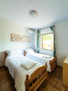 two beds in a room with a window at Casa Olivia - Casa indipendente nel centro di Cannigione a 3 minuti a piedi dal lungomare, 5 minuti a piedi dalla spiaggia più vicina e vicinissima alle spiagge più belle della Costa Smeralda in Cannigione