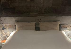 a white bed with four pillows and a brick wall at La Tour in Liège