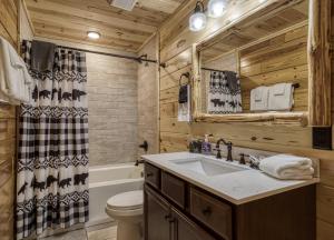een badkamer met een wastafel, een toilet en een bad bij Cozy Log Cabin, hot tub, pool table, pool access in Gatlinburg +17 foto's