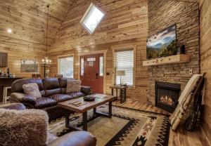 een woonkamer met een bank en een open haard bij Cozy Log Cabin, hot tub, pool table, pool access in Gatlinburg