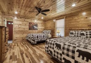 een slaapkamer met twee bedden en een plafondventilator bij Cozy Log Cabin, hot tub, pool table, pool access in Gatlinburg