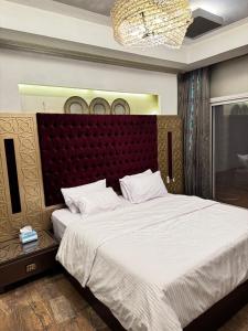 une chambre avec un grand lit avec une tête de lit rouge dans l'établissement فيلا داخل كمبواند ويستاون بيفرلي هيلز الشيخ زايد رقم هاتف صفر صفر اتنين صفر واحد واحد صفر اتنين اربعه ثلاثه صفر 222, à Sheikh Zayed