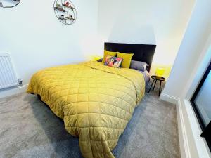 a bedroom with a bed with a yellow comforter at Abstract Escape! Stylish Apartment, Free Parking, 5 Minutes from Beach in Bournemouth