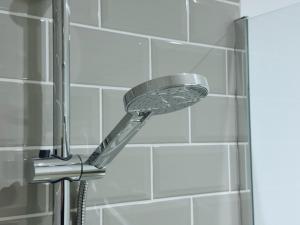 a shower with a shower head in a bathroom at Abstract Escape! Stylish Apartment, Free Parking, 5 Minutes from Beach in Bournemouth