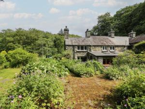 an old stone house in the middle of a garden at Glandwr Cottage in Llanbedr