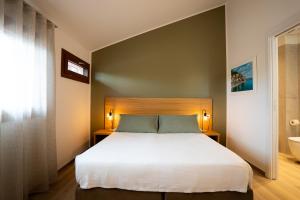 a bedroom with a large white bed and a bathroom at Locanda 19 al paradiso in Mirano