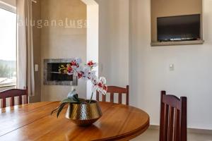 a dining room table with a vase with flowers on it at Ocean Breeze - Frente para o Mar in Jaguaruna