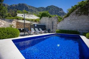 a blue swimming pool with mountains in the background at Villa GreyStone - House Podgora in Podgora